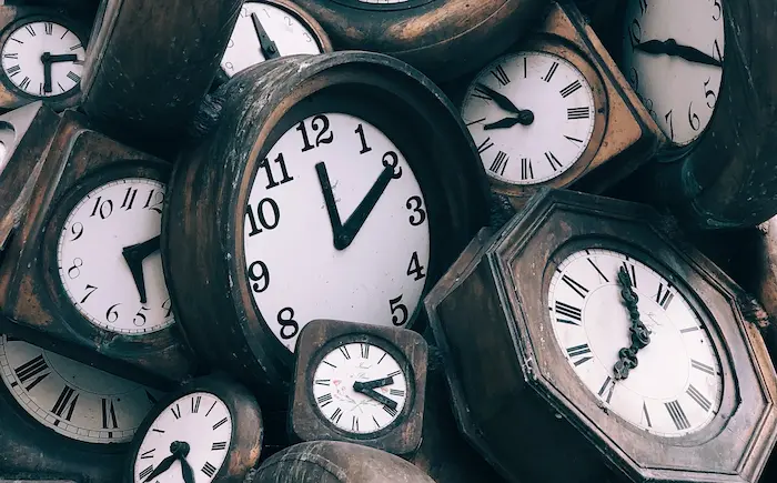 Wooden clocks of various shapes and sizes piled with their faces showing